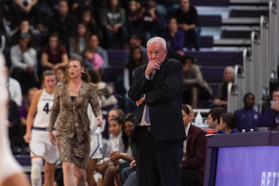 Coach in suit watches game from the sideline.