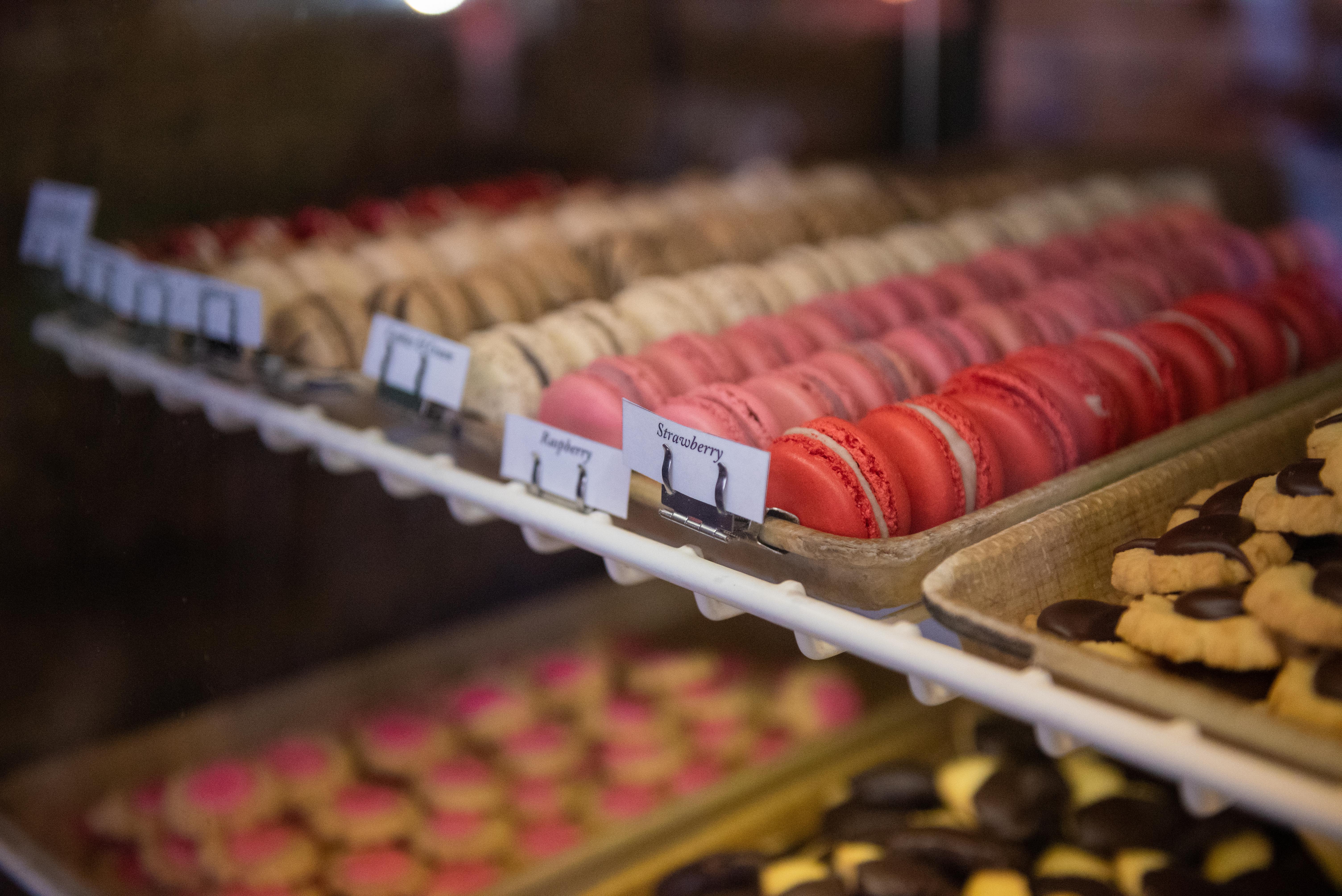 Rows of pink and brown macaroons in trays. 