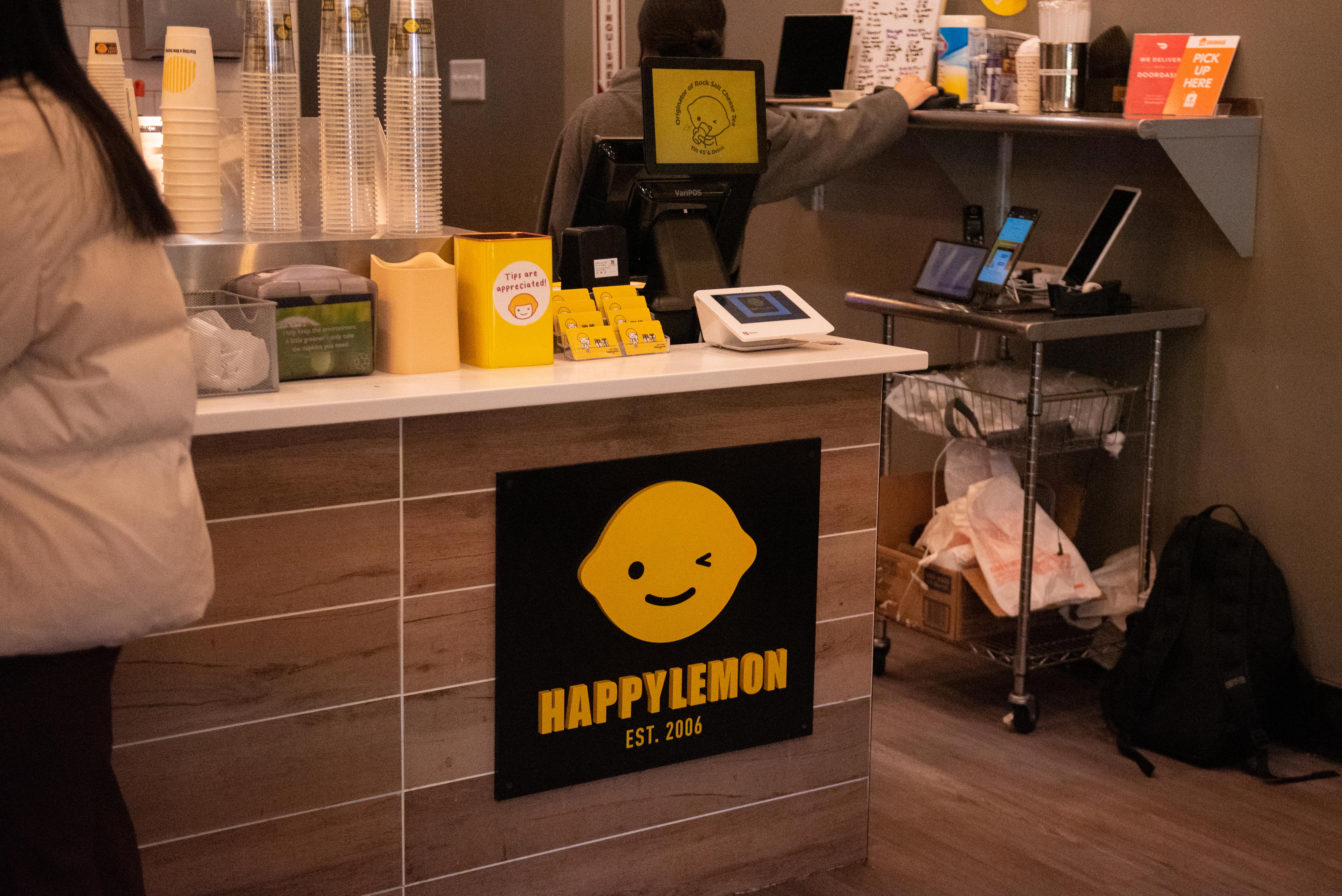 A shop counter with a yellow sign that reads “Happy Lemon.”