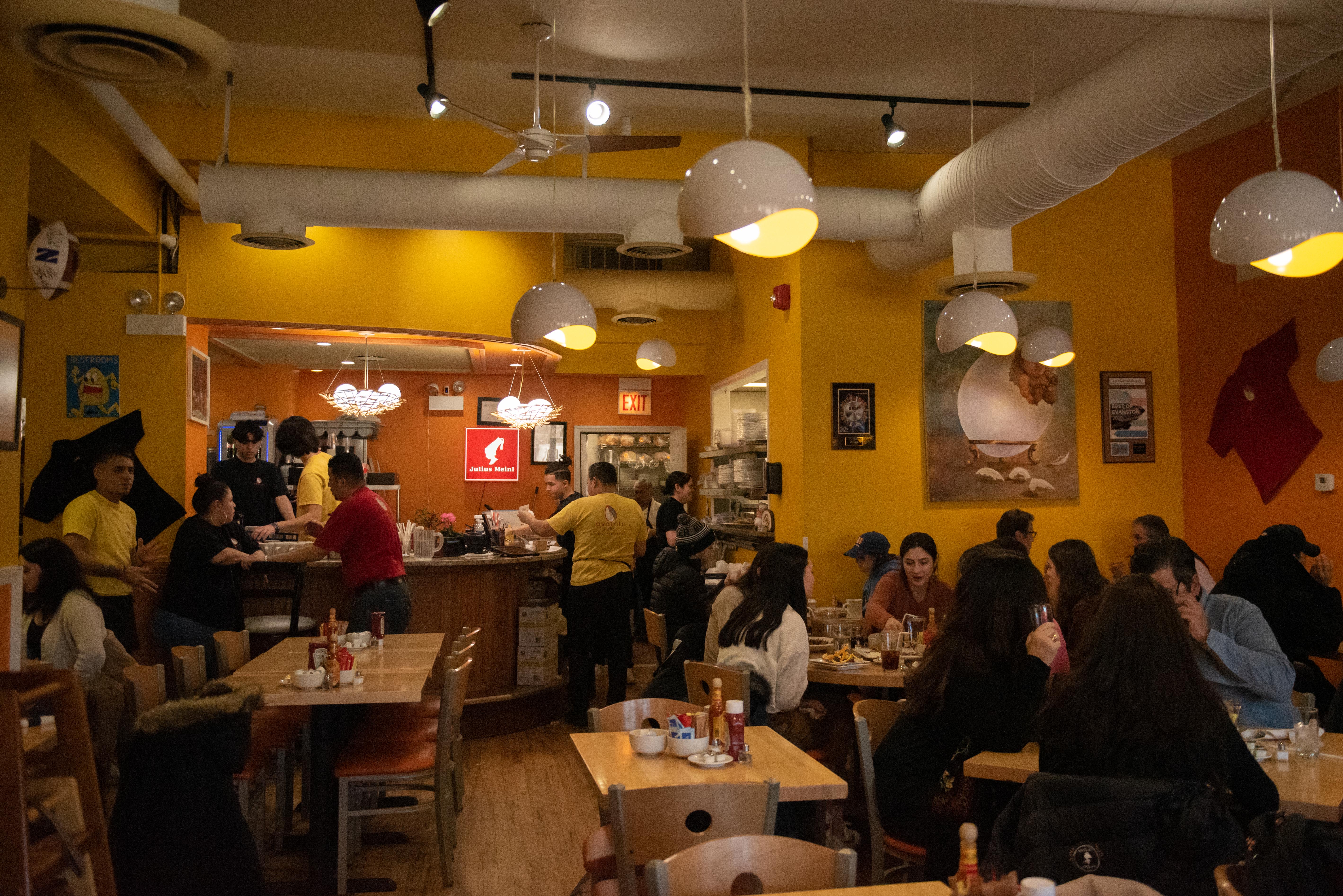 People sit in a restaurant with yellow walls.