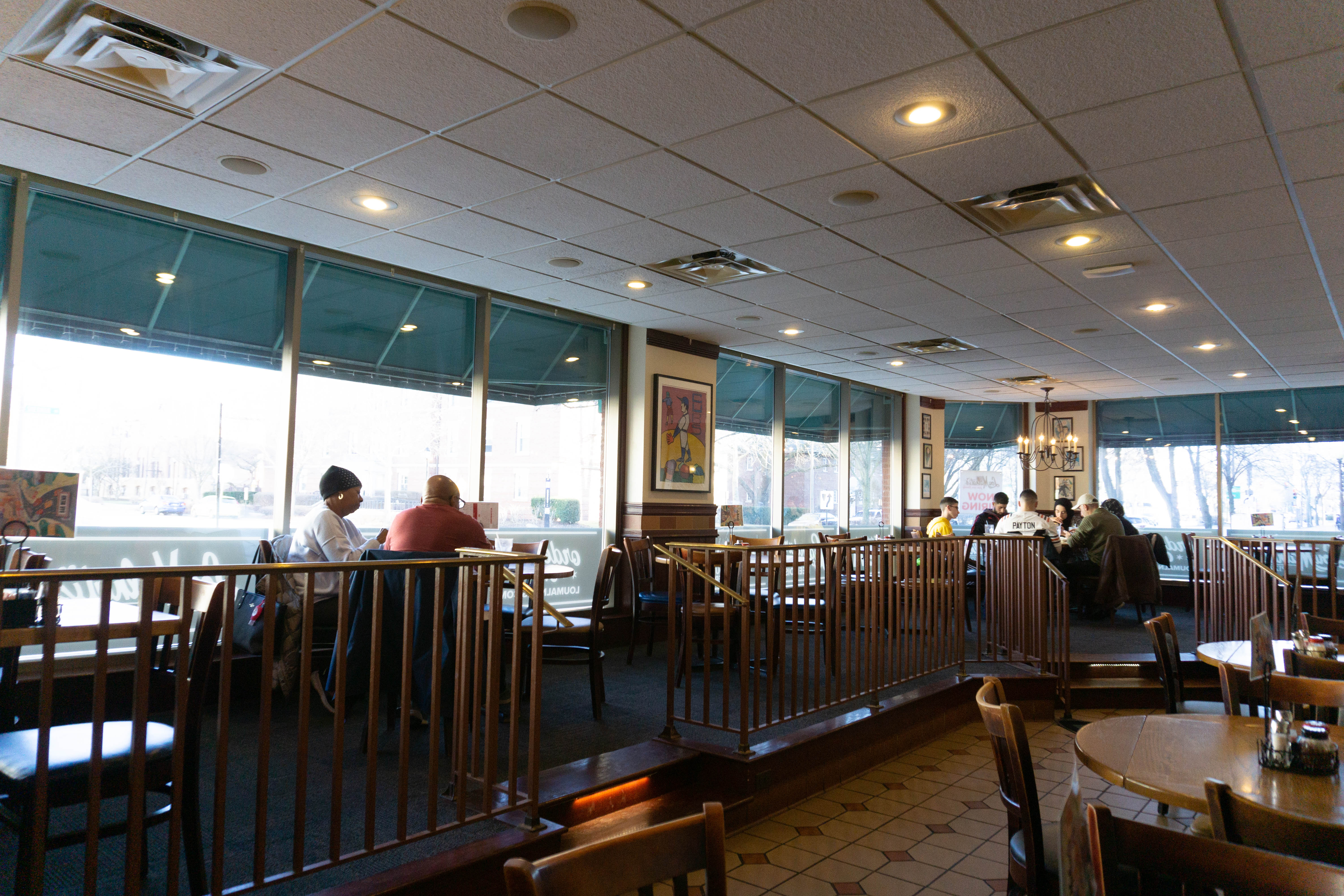 People eat in a room with floor-to-ceiling windows.