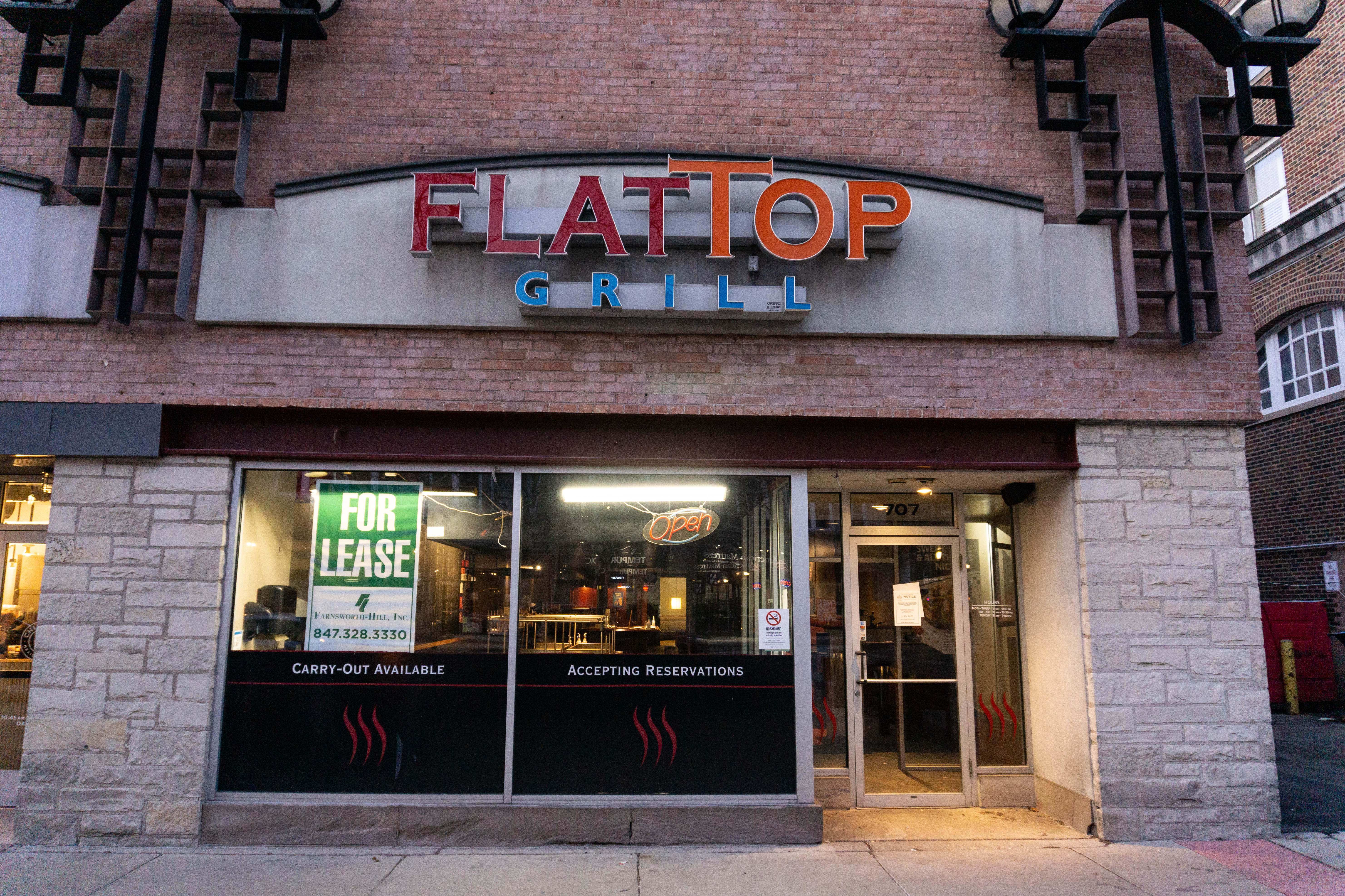 A sign reads “FLAT TOP GRILL” on a brick building.