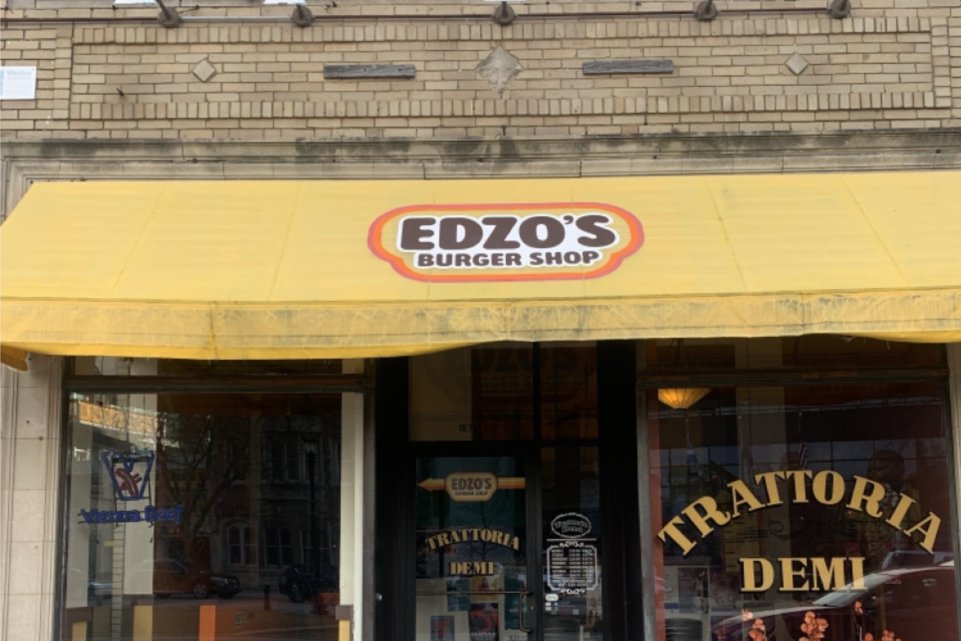 Edzo’s Burger Shop storefront with yellow awning and name of the store in brown letters.