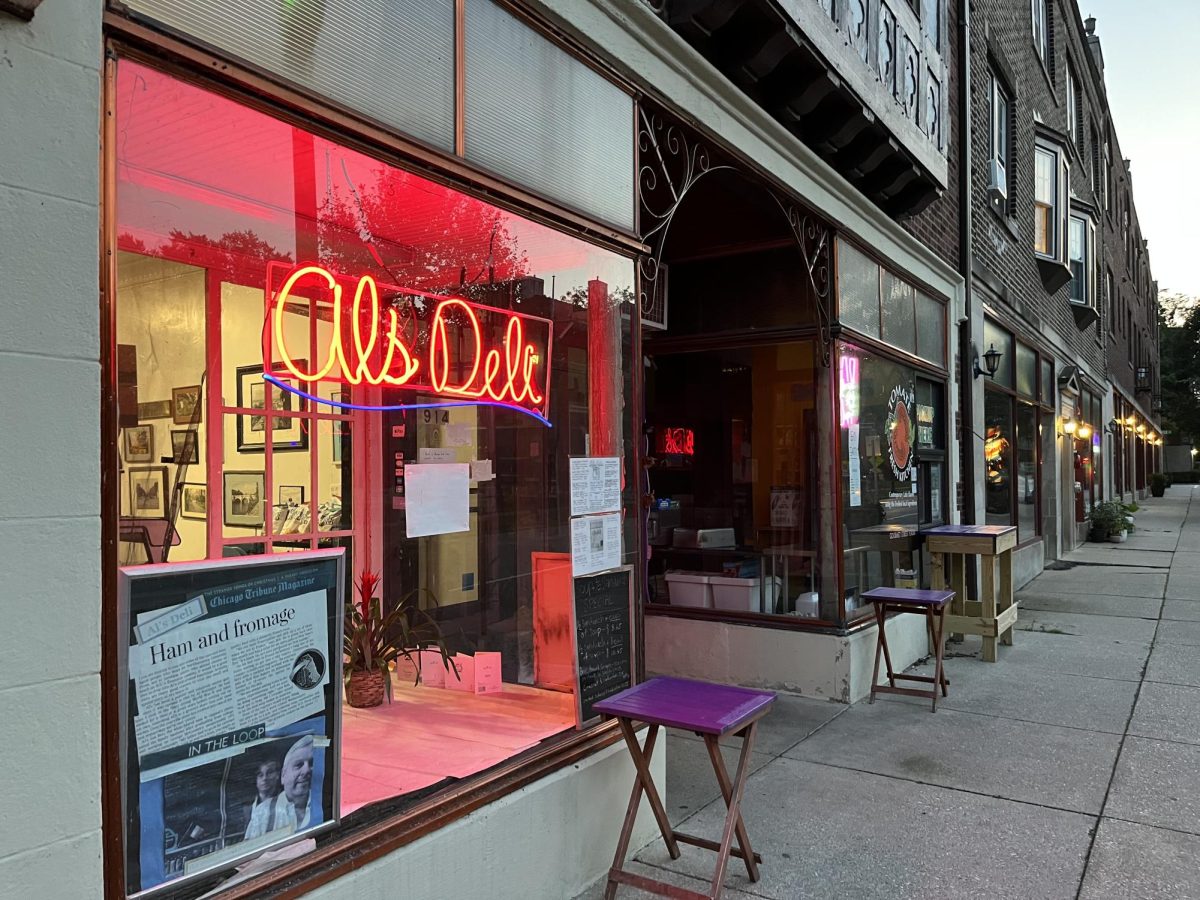 A store front is lit up by a large, red neon sign that says “Al’s Deli”.