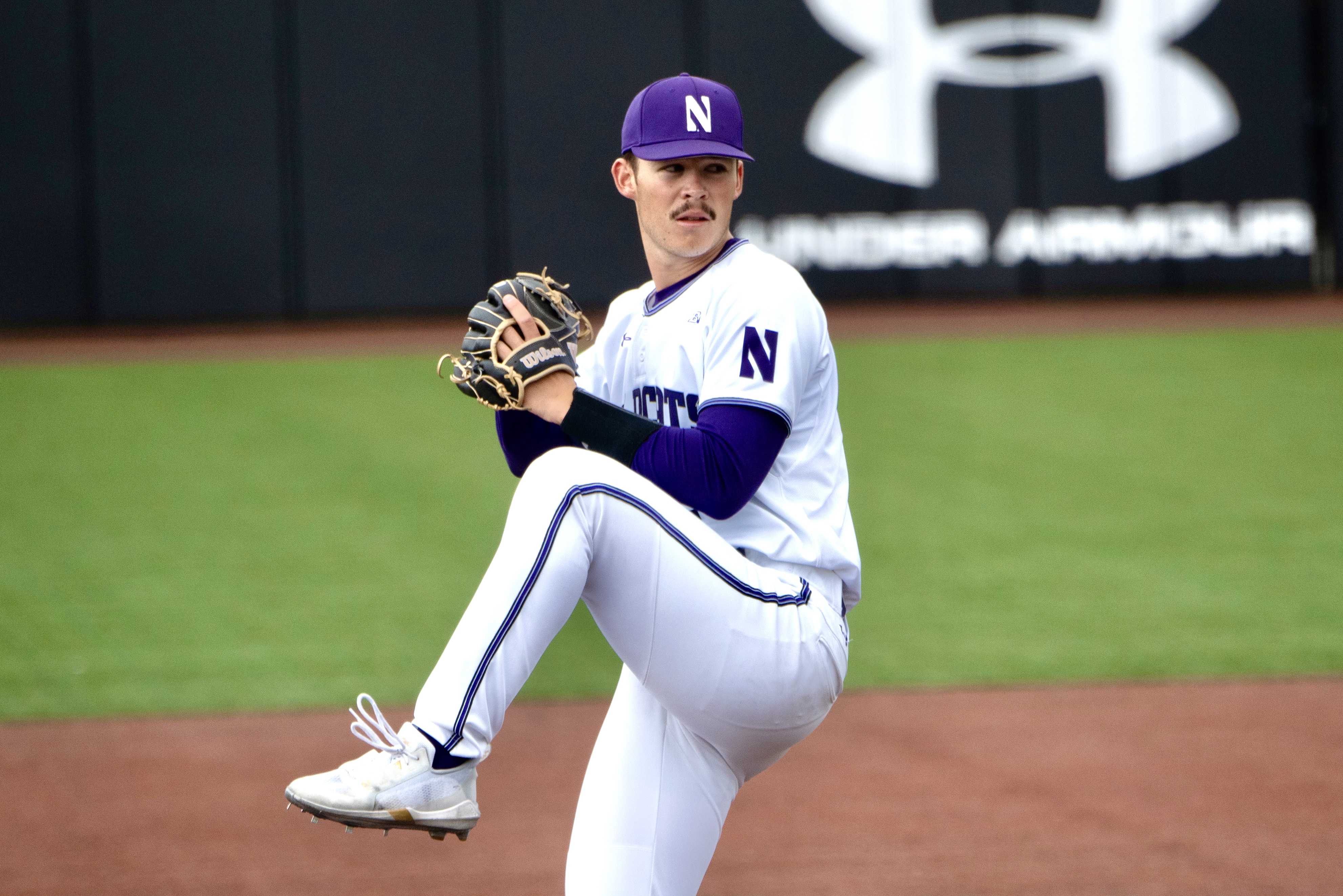 An athelete in white jersey holds a baseball with the gloves.