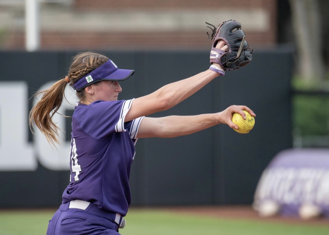 Girl in purple uniform throws softball.